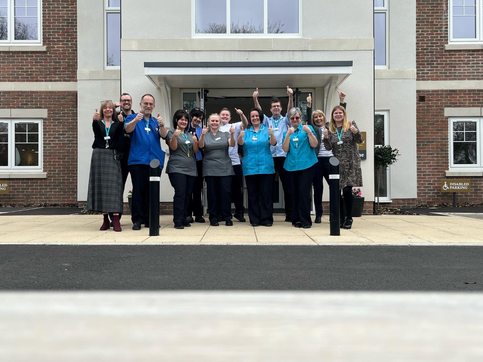 staff holding their thumbs up outside the home