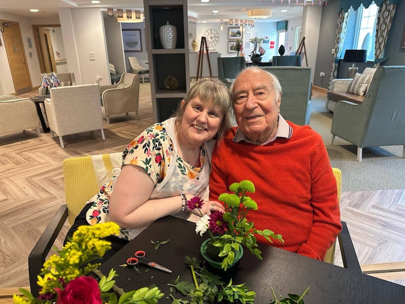 residents sat together smiling whilst doing flower crafts