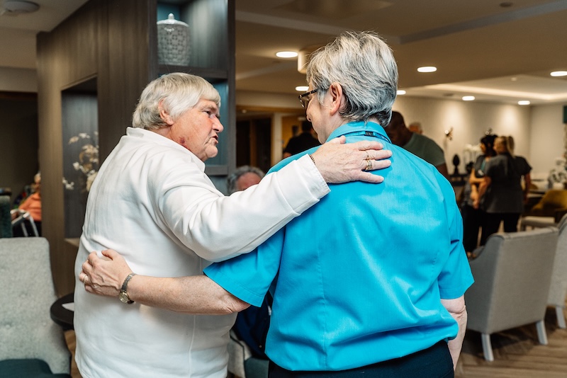 resident and carer chatting with their arms around each other