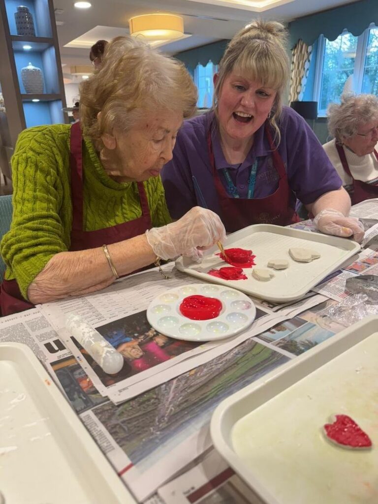 an older lady and carer painting crafts for valentines day