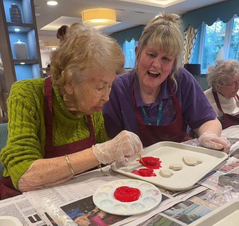 an older lady and carer painting crafts for valentines day
