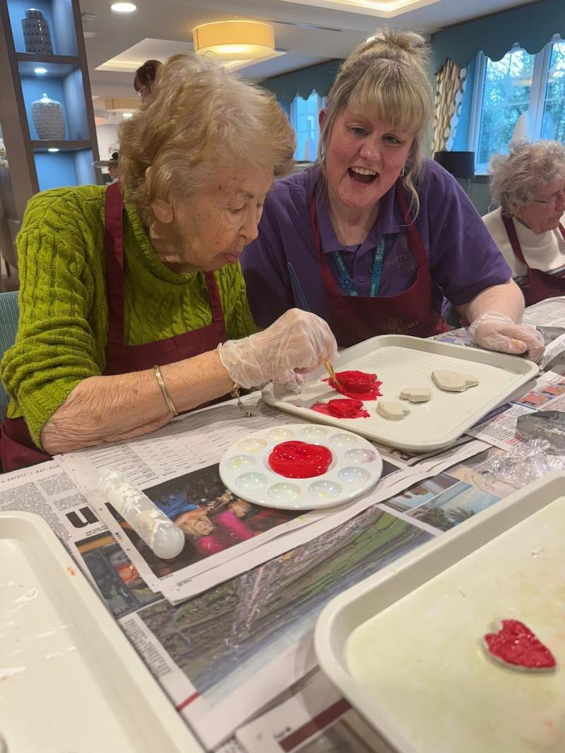 an older lady and carer painting crafts for valentines day