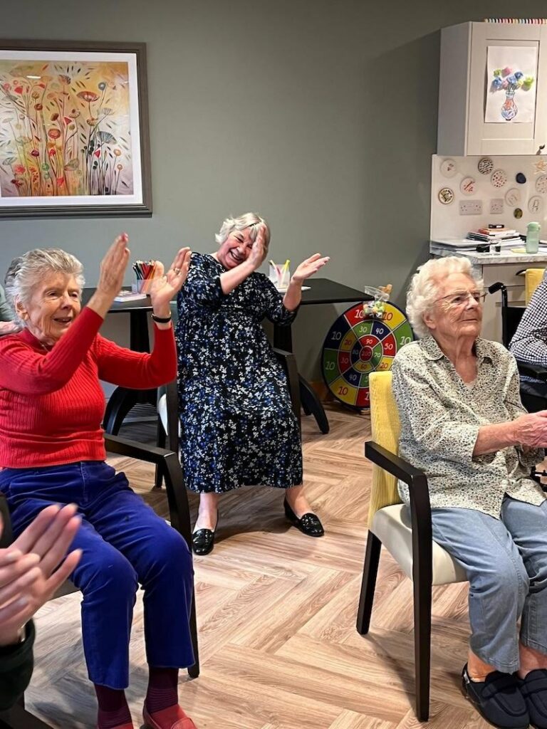 a group of elderly residents doing exercise in armchairs