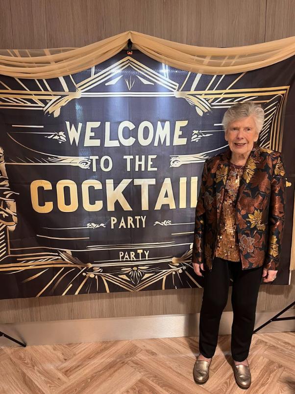 older lady stood in front of a cocktail party sign