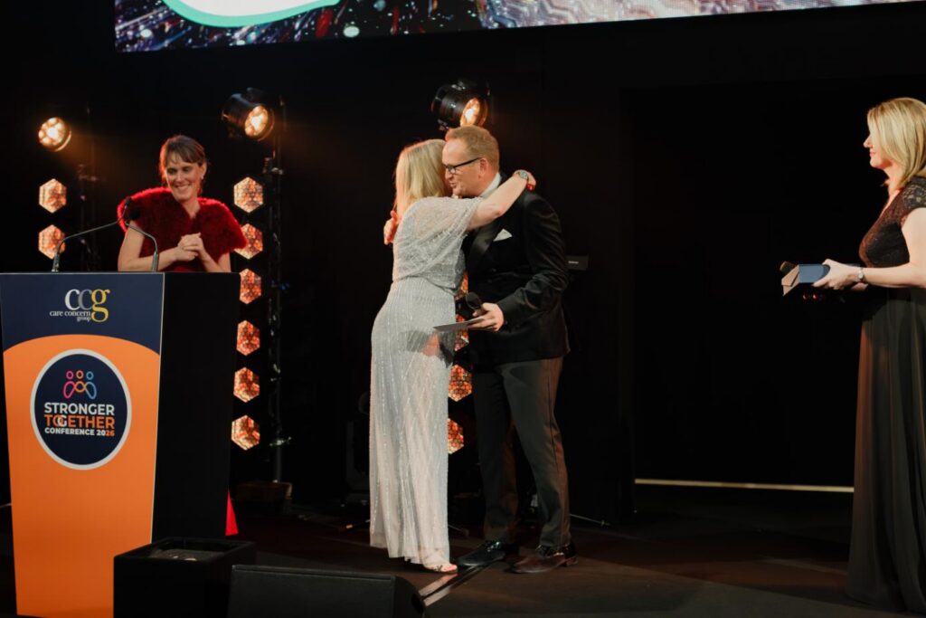 blonde lady up on stage hugging a man as she accepts award