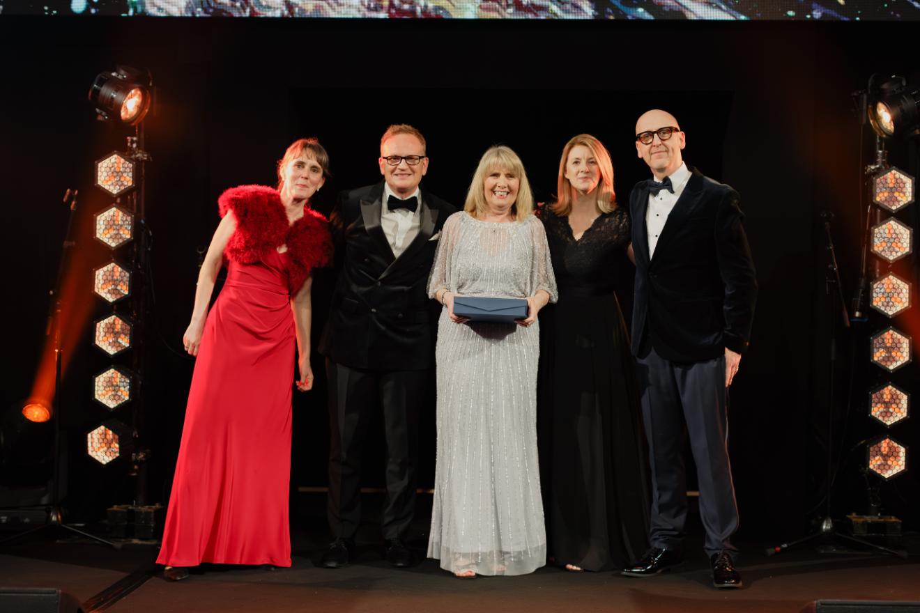 five people standing on stage posing for a picture at an award ceremony