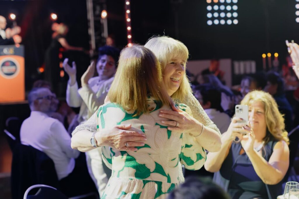 two ladies hugging in the crowd as one is getting an award