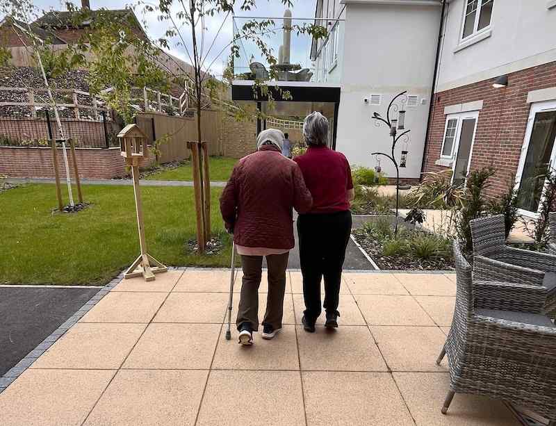 2 females walking in the garden holding onto each other