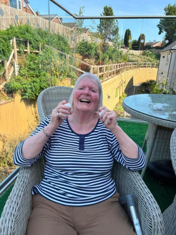 older lady sat in the garden smiling