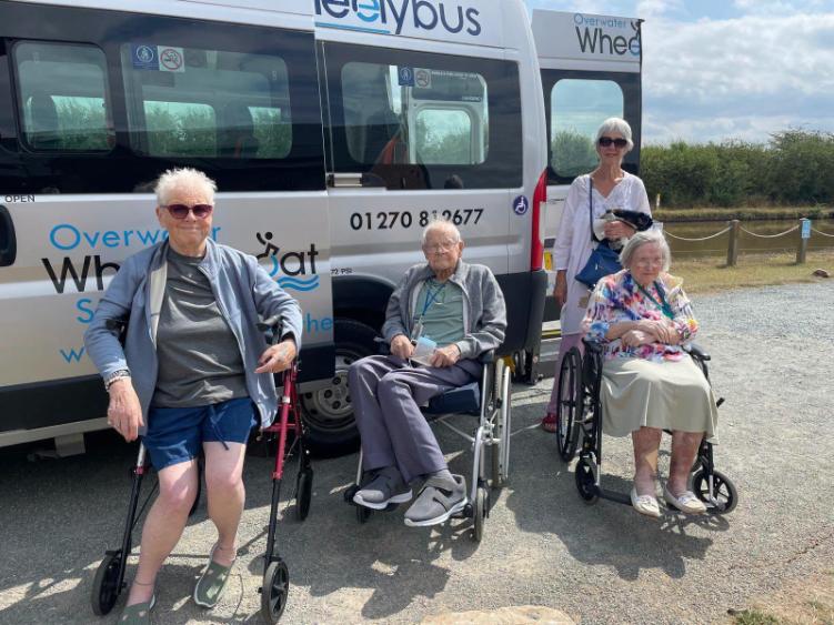older adults in wheelchairs by a bus